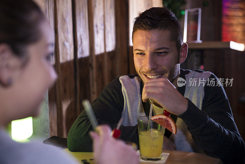 一对年轻夫妇在酒吧里聊天喝酒