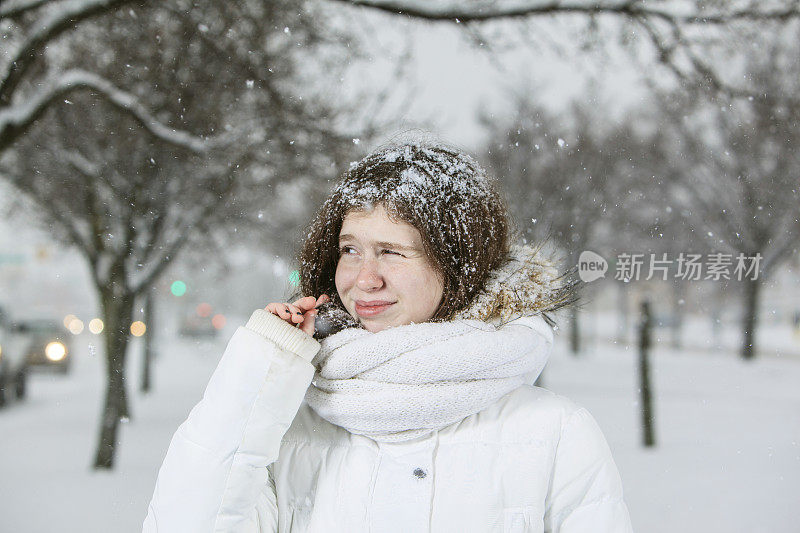 雪下穿着白色夹克的漂亮少女