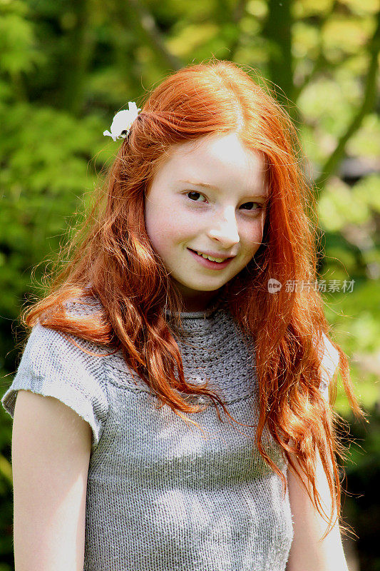 迷人的，快乐的女孩，长长的红头发在阳光下微笑