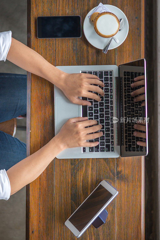 人的手打字笔记本与智能手机，平板电脑和旁边的咖啡