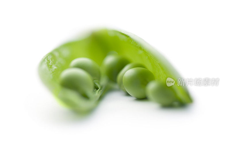 打开豆荚的特写显示绿色豌豆在白色的背景。