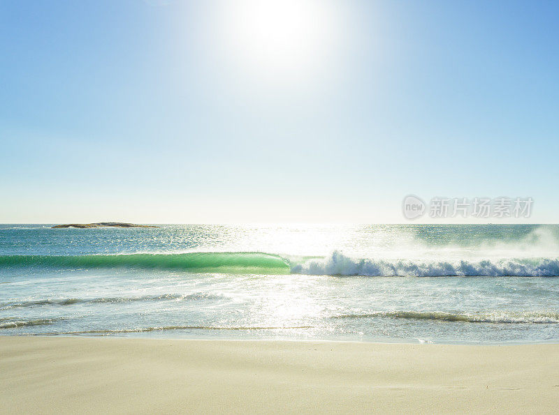 阳光明媚的海滩上，海浪反射出的阳光。