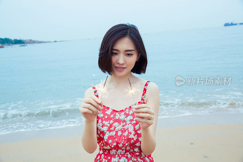 美丽的女人在海滩上玩烟花