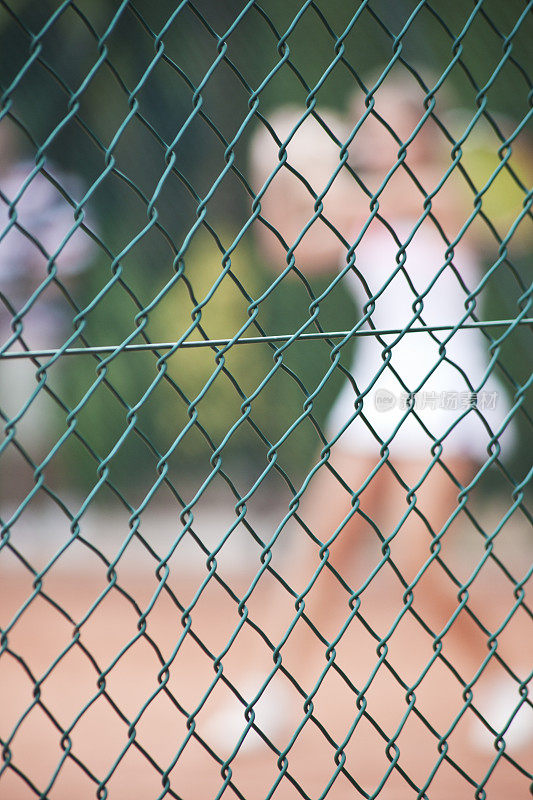 网球场和铁链围栏，球员在模糊的运动。