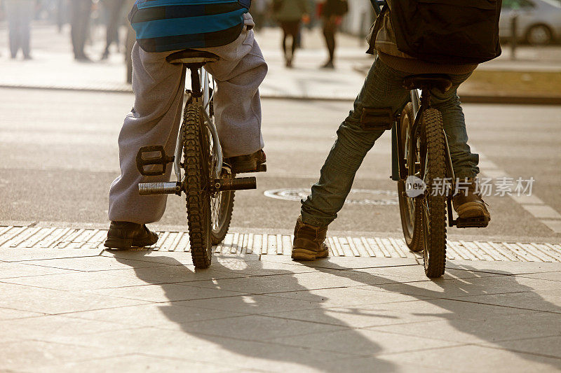 年轻的青少年朋友们骑着自行车穿过城市的街道，夏日