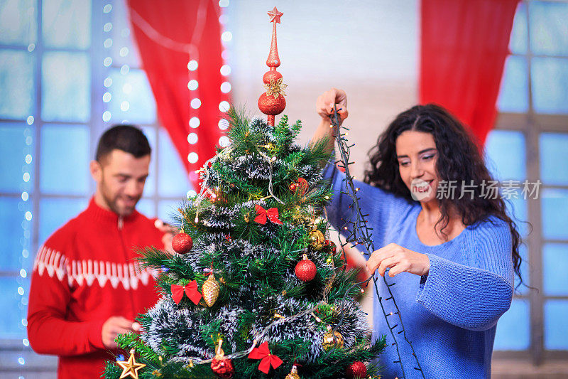 年轻夫妇在家里装饰圣诞树