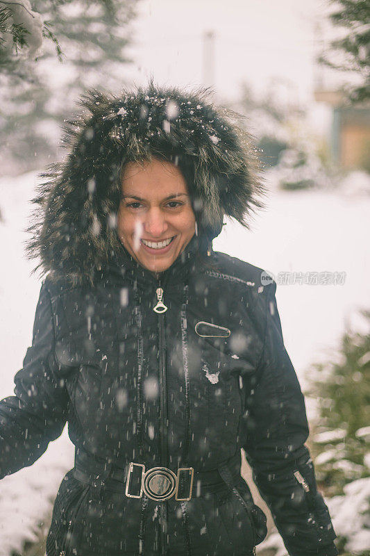 冬天的女人在寒冷的冬日里，在雪地里仰望着快乐的微笑。