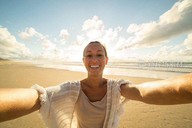 日落时分，白种女性在海滩上自拍