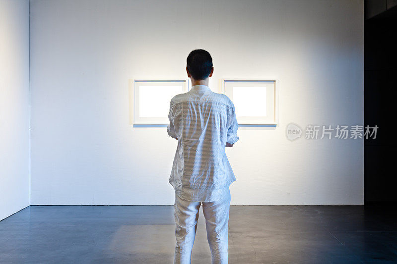 一个人在画廊里看白色的画框