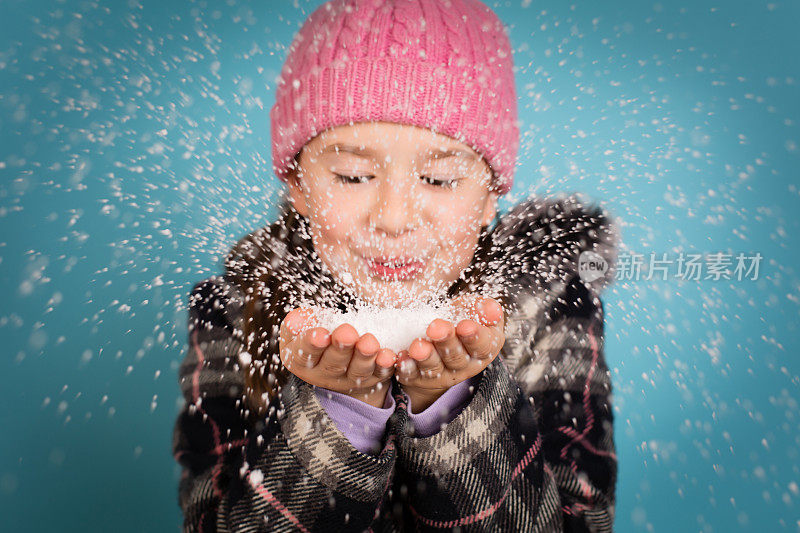 快乐的小女孩在镜头前吹了一把雪