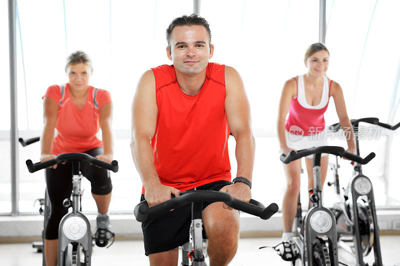 年轻人在健身房锻炼自行车。