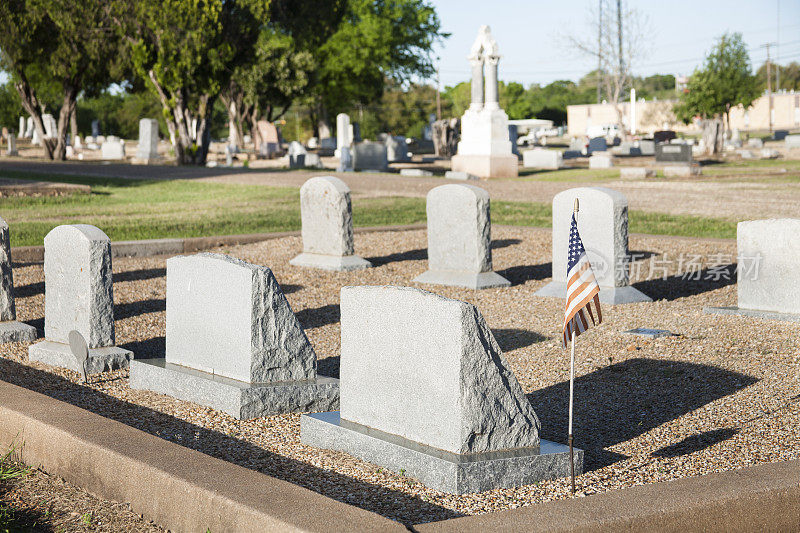 美国国旗在坟上，墓碑在墓地。其他的墓碑。