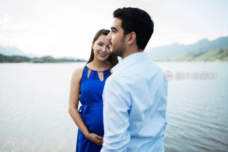 年轻孕妇微笑着站在丈夫身后