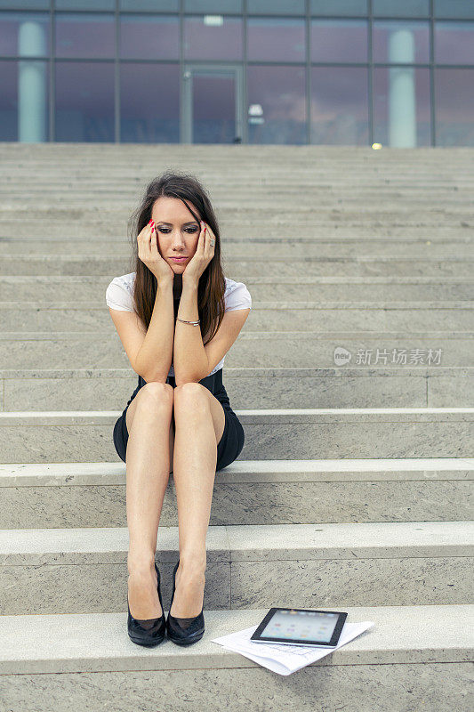 沮丧的女商人坐在楼梯上