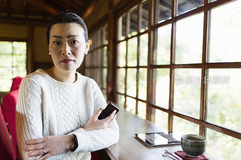 一个在咖啡馆用智能手机的成熟女人