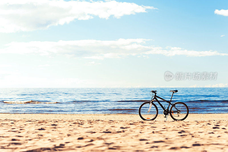 一辆自行车站在沙滩上的蓝色海景背景。