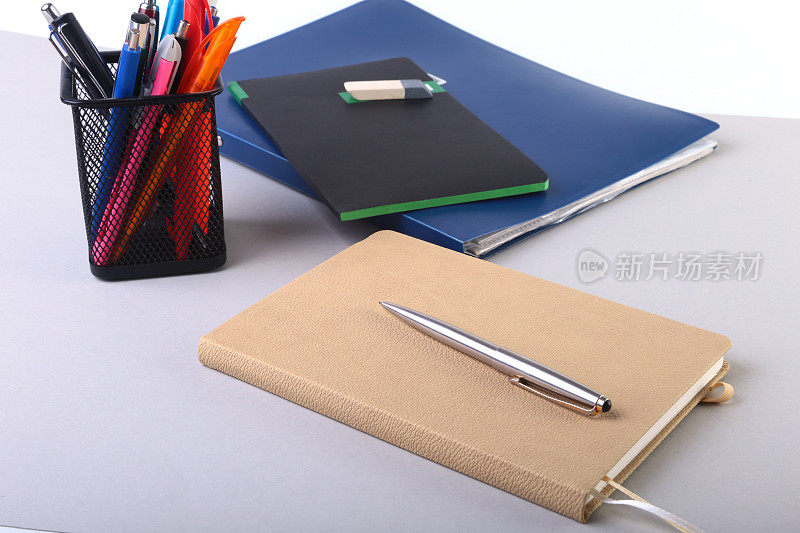 白色的桌子上放着彩色的笔记本和办公用品。