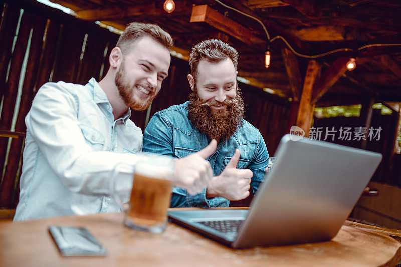 两个竖起大拇指的大胡子男人一边喝啤酒一边开视频会议