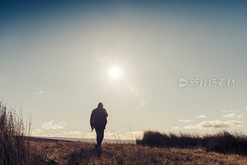 男人在秋日的阳光下徒步旅行。