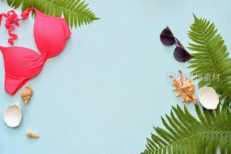 女性夏季比基尼泳装和配件拼贴在蓝色与棕榈树枝，帽子和太阳镜。
