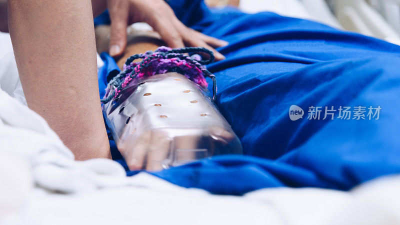 在医院给病人静脉注射生理盐水的亲属和病人的手牵着老人的手，用自制的束缚手套