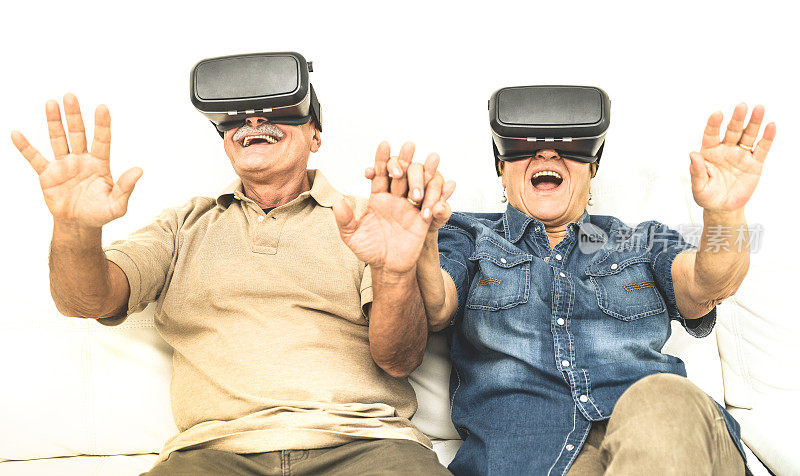 老两口玩得很开心，戴着虚拟现实耳机坐在沙发上-快乐退休的人用现代vr眼镜-新趋势和技术概念和有趣的活跃的老年人