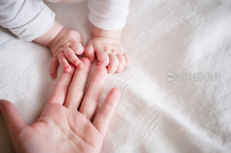 母亲用手指握着新生婴儿的手
