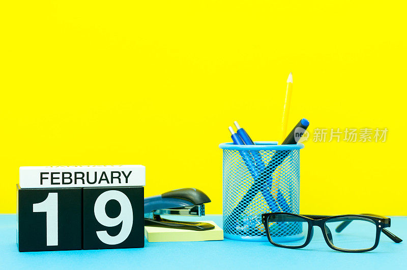 2月19日。月2月19日，日历以黄色为背景配办公用品。冬天