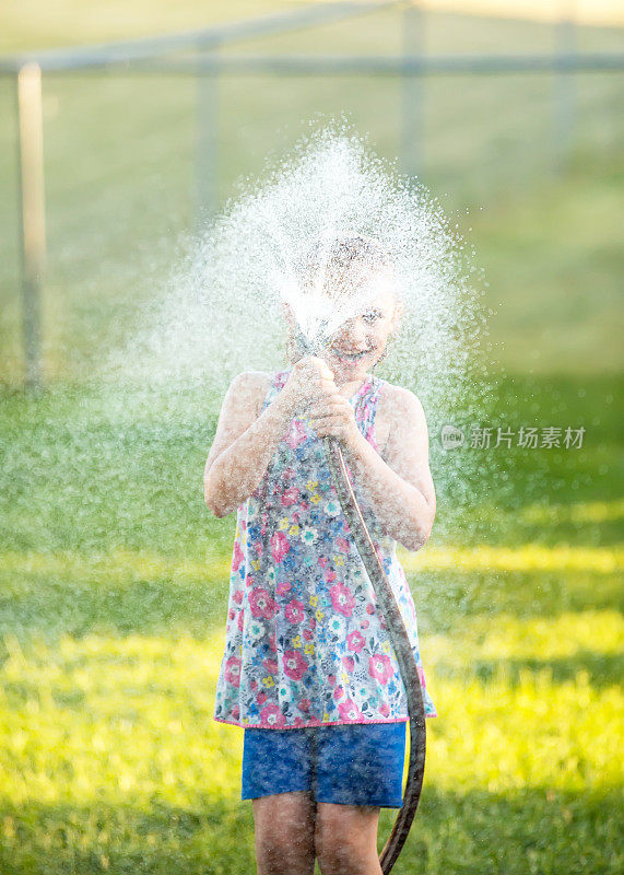 女孩用水龙带向相机喷水