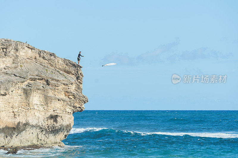 悬崖上的年轻雄性把他的冲浪板扔进海里准备跟着跳下去