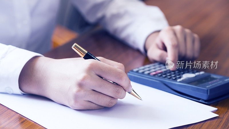 商人用计算器、纸和铅笔进行财务分析。财务图表数据