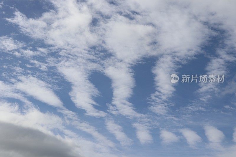 蓝色天空映衬着蓬松、缕缕白云的特写