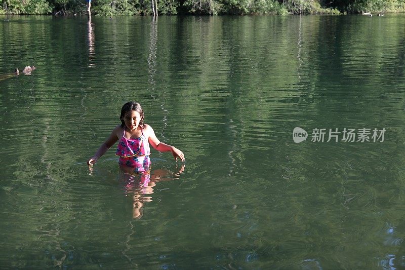 女孩走进淡水湖，在一根圆木上保持平衡