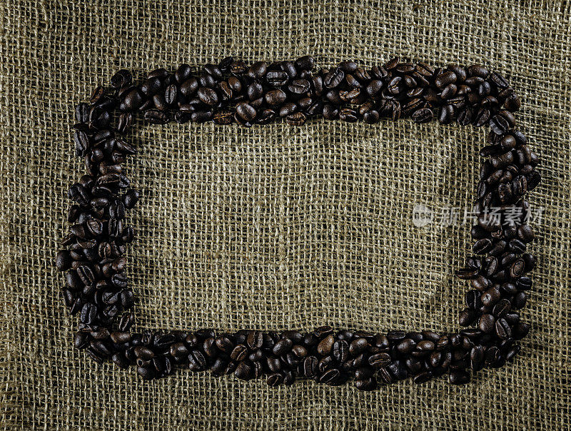烤生咖啡豆制作框架在黄麻背景与复制空间