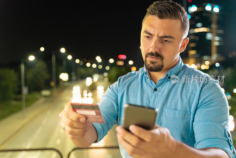 男人在网上购物使用信用卡和智能手机查看和输入他的个人数据