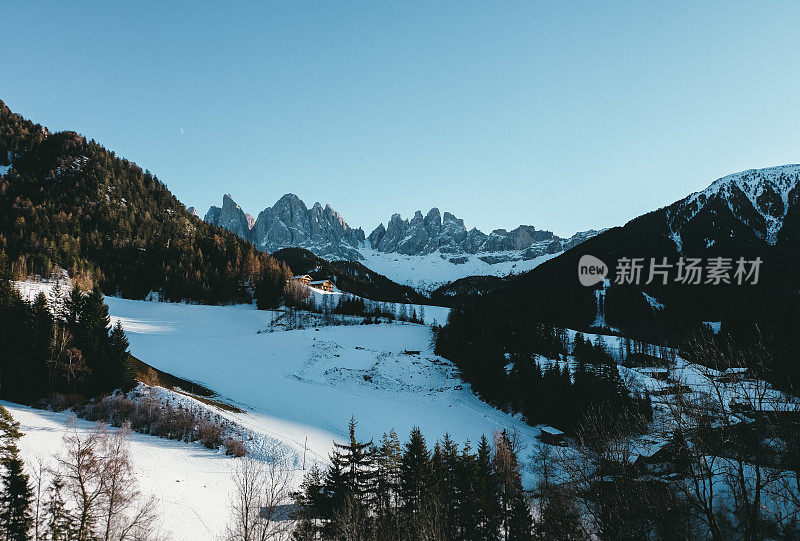 风景如画的冬季小山村，教堂和白云石山峰在意大利