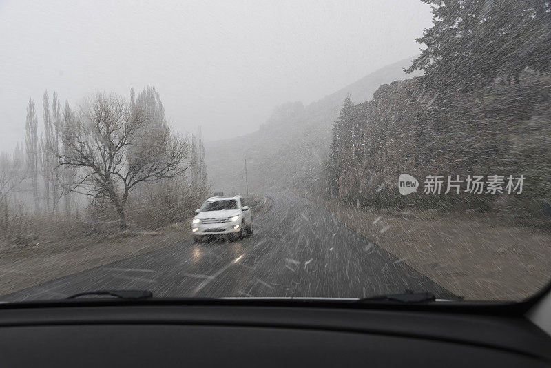 在下雪的道路上行驶的汽车在相反的方向，湿滑的信号和下一个左转弯