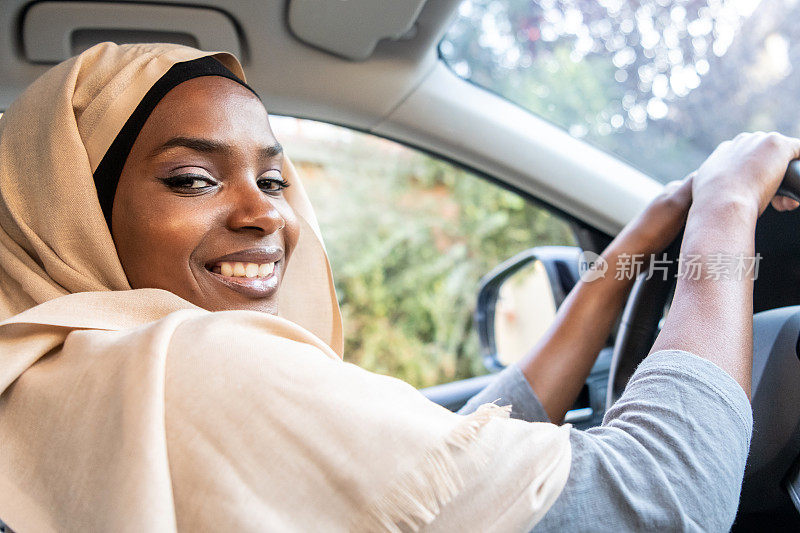 微笑的黑人穆斯林妇女开着她的车
