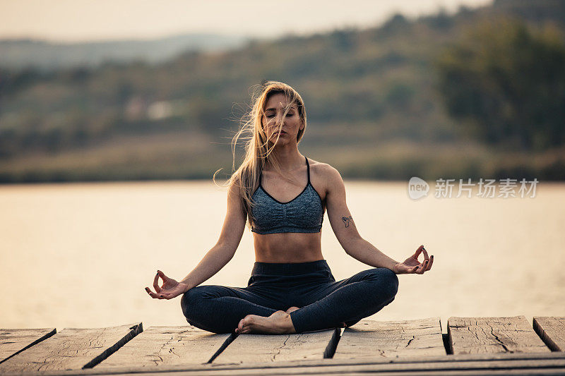 健康和运动的年轻女子在湖边做瑜伽