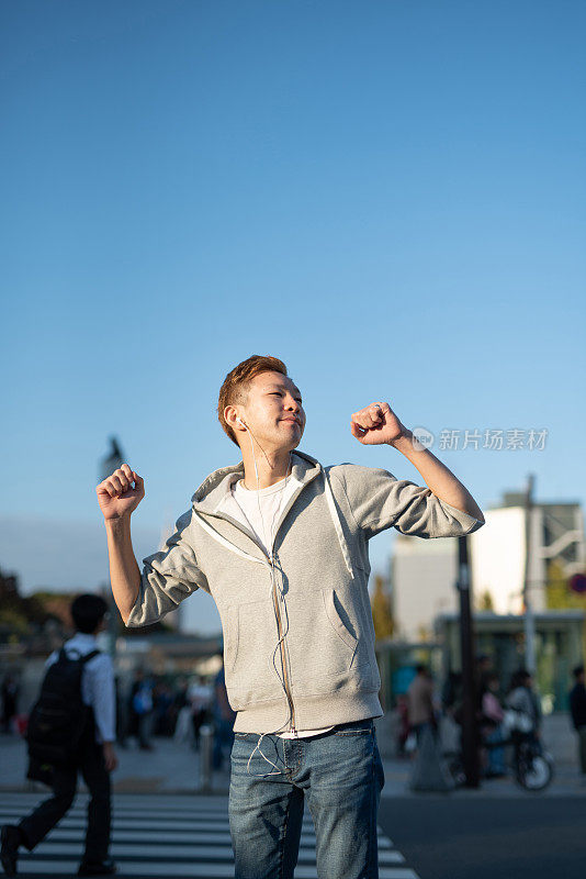 年轻人戴着耳机听音乐，在街上跳舞