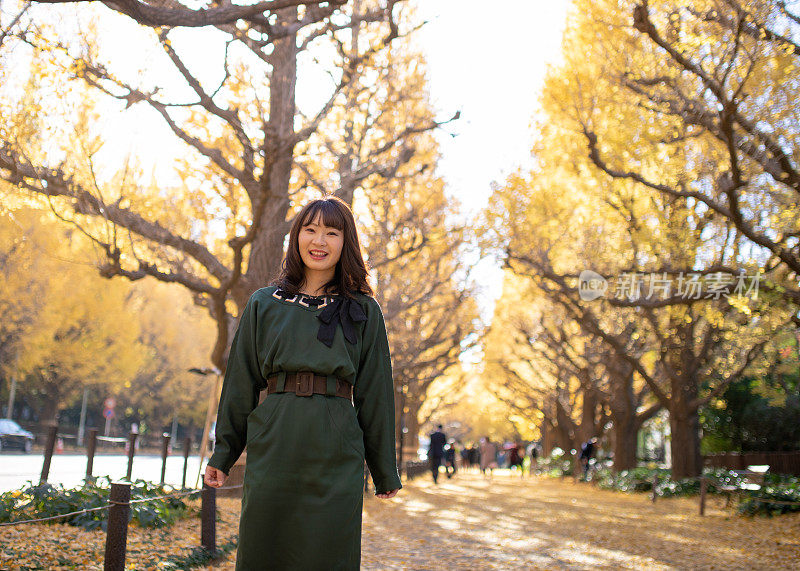 年轻女子走在银杏叶下