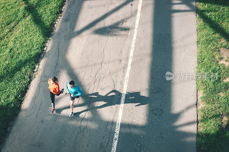 一对情侣在柏油路上奔跑的鸟瞰图