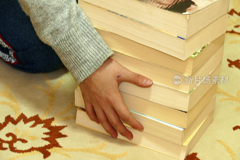 厚厚的书和一个想要拿书的人，一个人的手触摸着厚厚的书，厚厚的小说摞在一起，