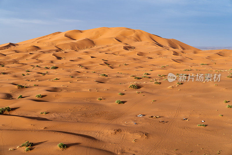巨大的橙色沙状沙丘和多云的天空在Merzouga沙漠，摩洛哥。