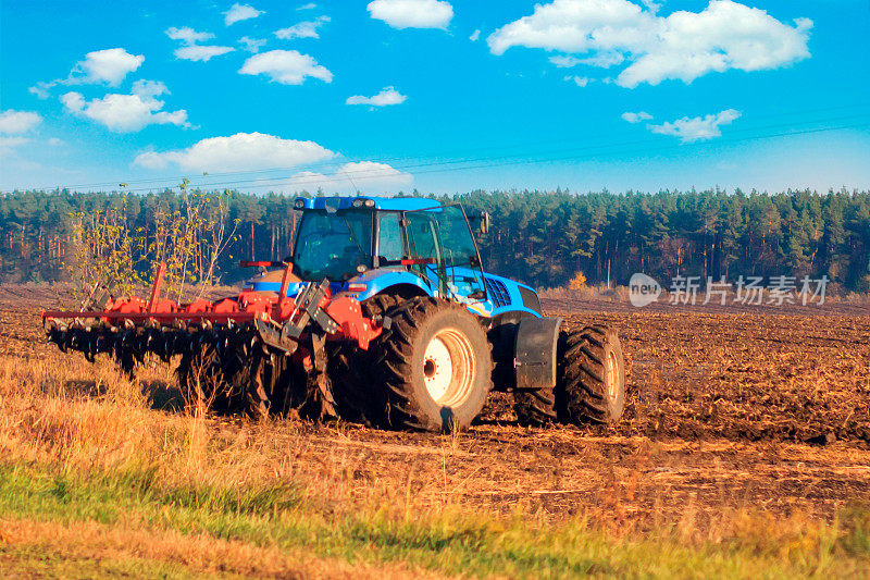 农民在拖拉机上用苗床中耕机准备土地，作为早春季节在农田中进行的农业工作的预播活动的一部分。