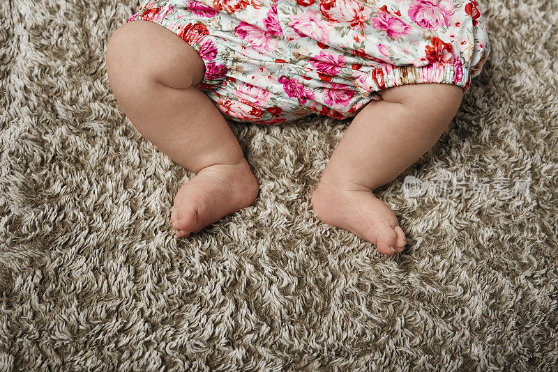 小女孩的小腿躺在地毯上