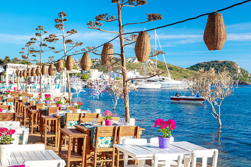 在美丽的爱琴海附近的博德鲁姆镇，爱琴海海滨风格的五彩桌椅和鲜花。