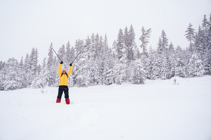 冬天的旅行者。年轻的女游客走在深深的雪中，享受冬天的山。肖像。