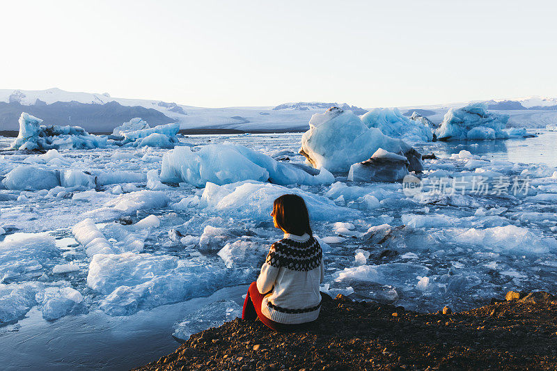 冰岛Jokulsarlon冰川泻湖上，一名女子与明亮的冬日日落相遇