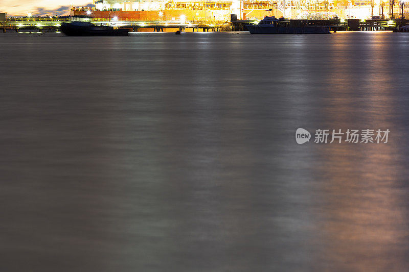 海湾在夜晚与油轮在炼油厂港口和城市天际线，背景与复制空间